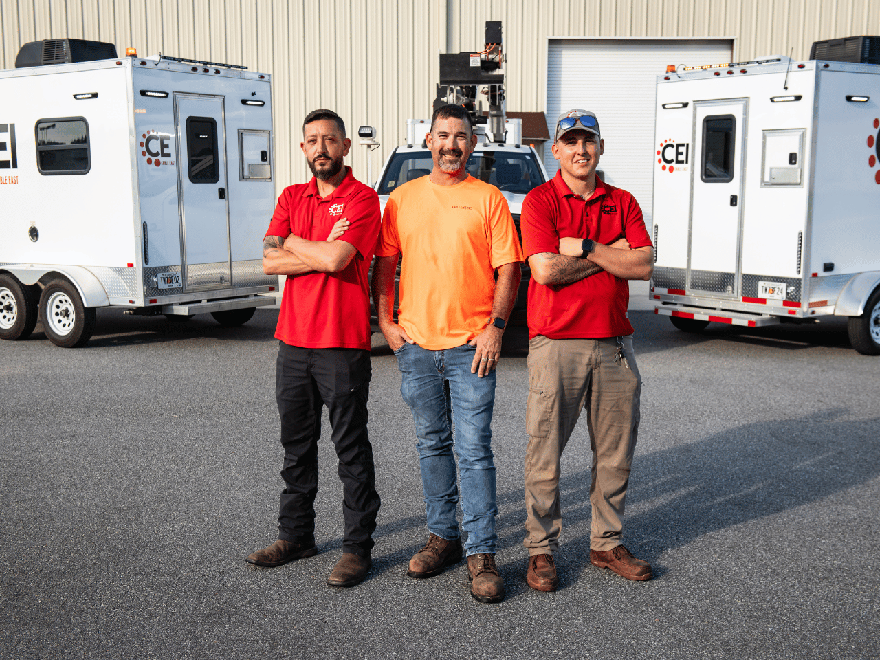 Cable East team members pose in front of equipment trailers.